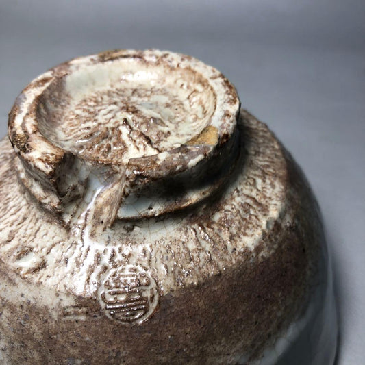 Split foot (warikodai) of a Hagi ware tea bowl, showing hand-trimming marks, exposed clay and stained crazing — the areas where a bowl's age is read